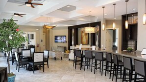 A modern kitchen with a large island, bar seating, and a dining area with chairs and tables.