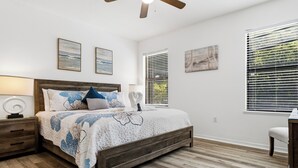Un dormitorio con cama de madera, una mesita de noche, un escritorio y una silla.
