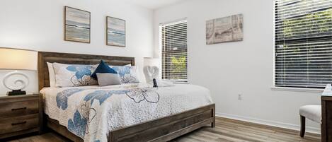A bedroom with a wooden bed, a nightstand, a desk, and a chair.