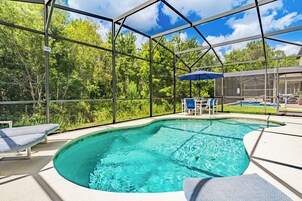Piscina com cobertura de vidro, rodeada por espreguiçadeiras e um espaço de pátio.