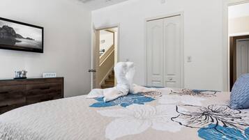 A bedroom with a bed, a dresser, a framed picture, and a staircase leading to another room.