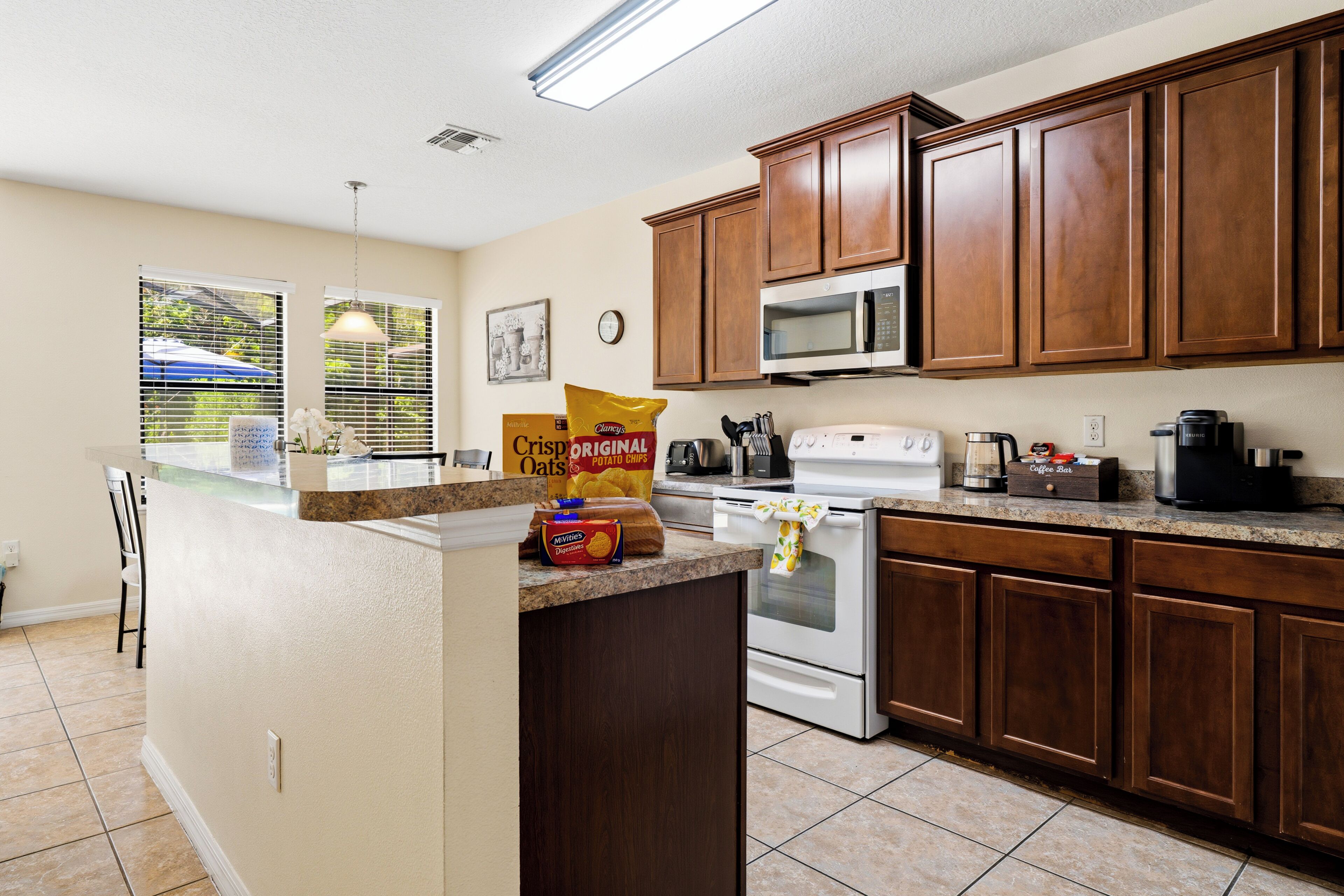 A kitchen with wooden cabinets, a microwave, a stove, and various kitchen items on the counter.