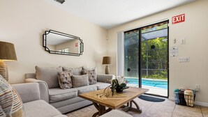 Una sala de estar con sofá, mesa de centro y vista a la piscina.