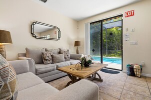 Sala de estar com sofá, mesa de centro e vista para a piscina.
