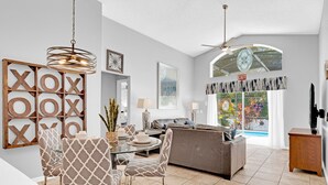 A modern living room with a dining area, a grey sofa, and a ceiling fan. - Allamanda Holiday Home 4 Bedroom (Kissimmee)