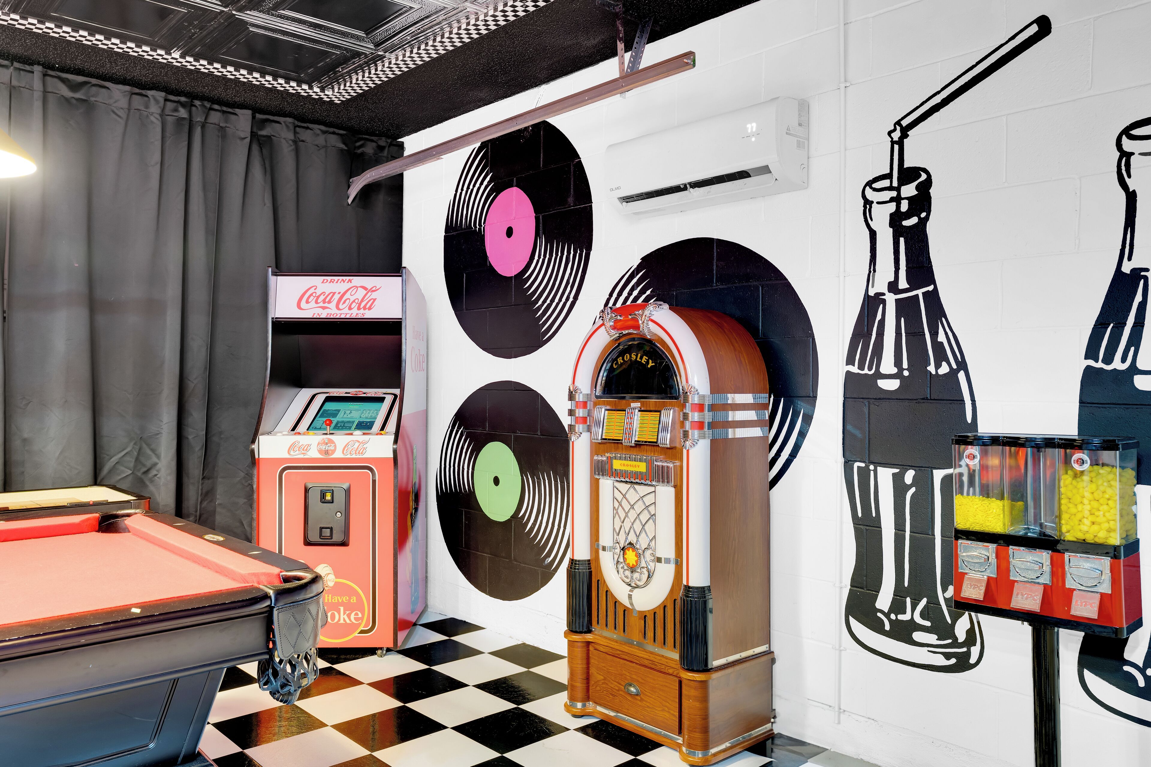 A retro-themed room with a jukebox, a Coca-Cola vending machine, and a jukebox with a record player.