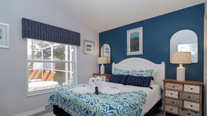 Een slaapkamer met een bed, nachtkastjes, een raam met uitzicht en een stoel ernaast.