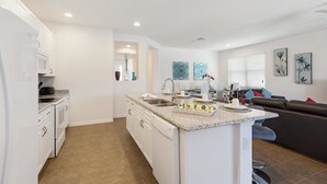 Une cuisine moderne avec des meubles blancs, un plan de travail en granit et un lave-vaisselle encastré.