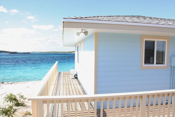 Una casa frente al mar con terraza de madera y vista al océano.
