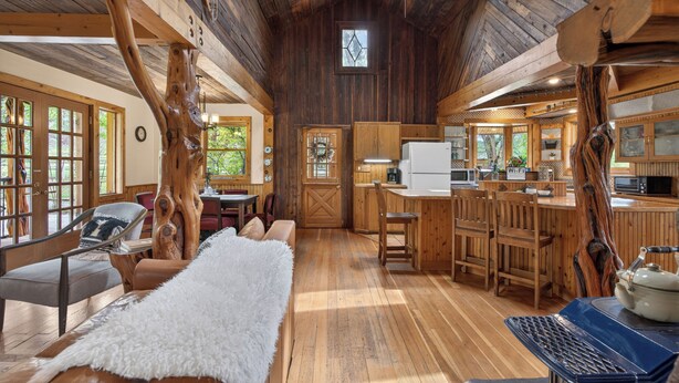 L’intérieur d’un chalet rustique, avec des murs en bois, un coin repas, une cuisine et un espace salon confortable.
