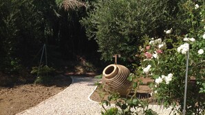 Een grindpad in een tuin, omringd door verschillende planten en een grote decoratieve pot.