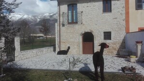 A stone building with a courtyard, a gate, and a mountain view. - Small Alvitano shelter (Alvito, Frosinone)