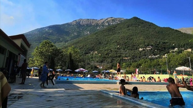 A pool area with a mountain backdrop, surrounded by umbrellas and people. - Small Alvitano shelter (Alvito, Frosinone)
