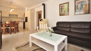 Una sala de estar moderna con una mesa de centro de vidrio, un sofá de cuero marrón y un comedor con sillas de madera y una mesa blanca.