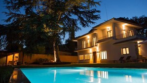 A two-story house with a swimming pool at dusk.