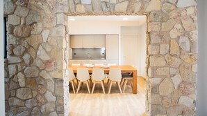 A stone-framed doorway leading to a kitchen with a wooden table and chairs.