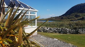 Une maison moderne en verre offrant une vue sur un lac et, au loin, sur une montagne.