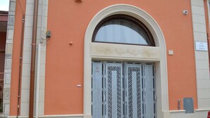 A building with a large arched entrance, a decorative frieze above the door, and a sign indicating the street name. - Salento Rosa dei Venti - Scirocco (Surbo)