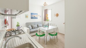 A modern kitchen with a gas stove, sink, and a dining area with a table and chairs. - Salento Rosa dei Venti - Scirocco (Surbo)