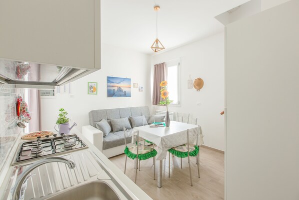 A modern kitchen with a gas stove, a sink, and a dining area with a table and chairs.