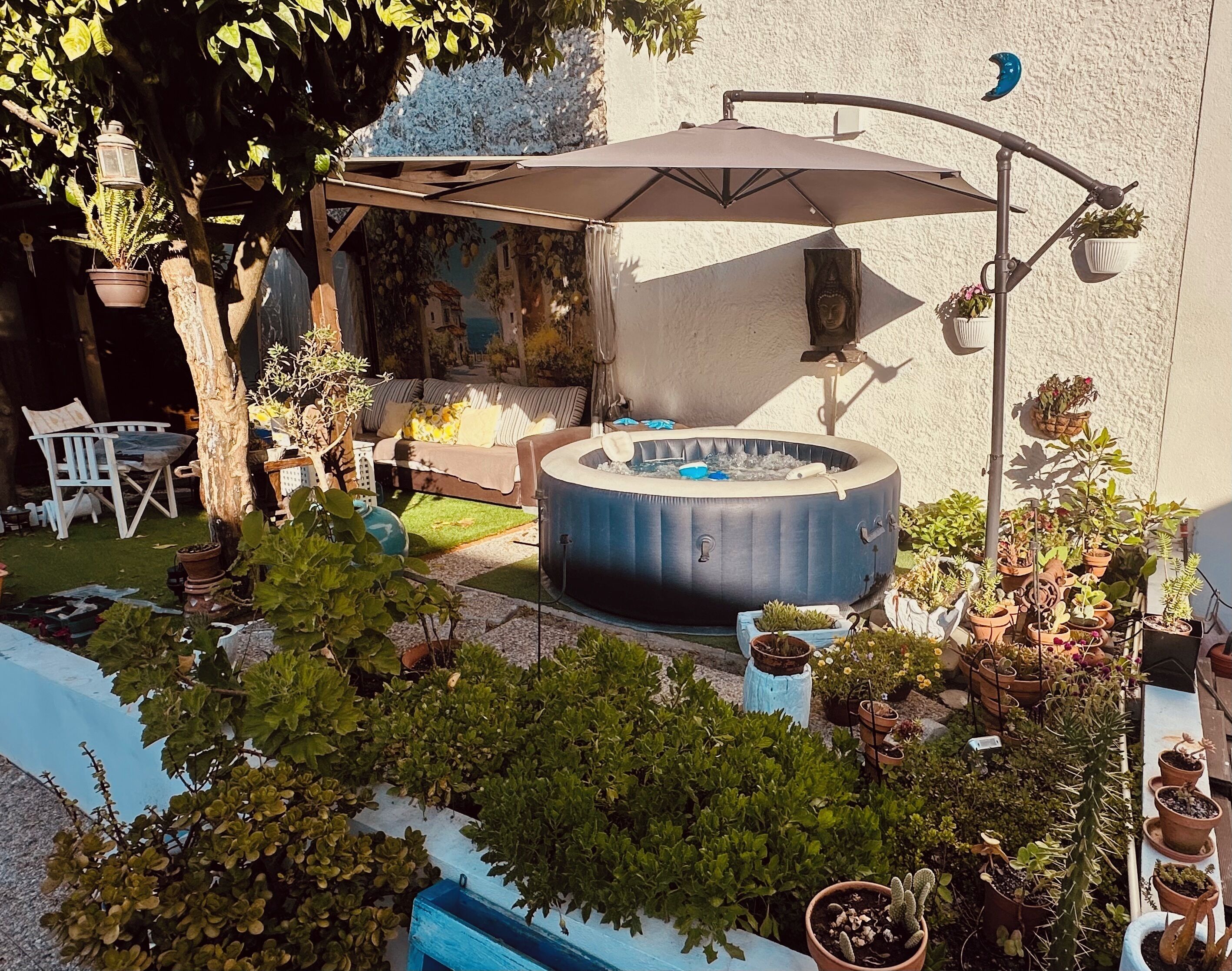 A patio area with a hot tub, outdoor seating, and various potted plants.