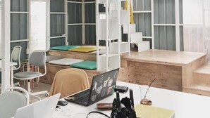 A modern office space with a high ceiling, white shelving units, and a wooden desk area. - Concept Yard Chiangrai - Adults Only - Hostel (Chiang Rai)
