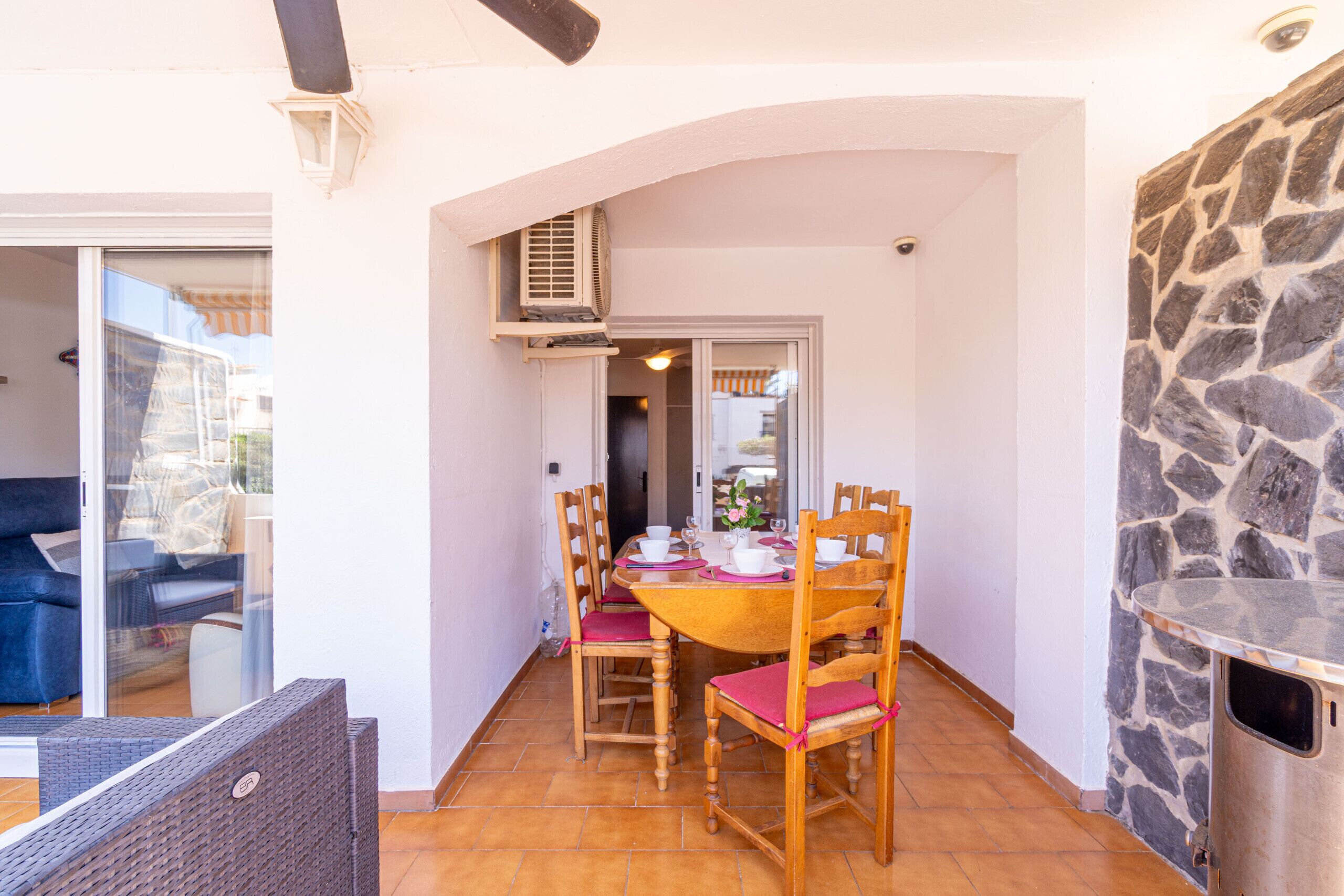 A dining area with a round table, wooden chairs, and a stone wall.