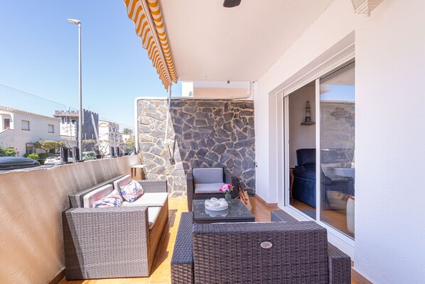 A balcony with wicker furniture, a stone wall, and a view of the city.