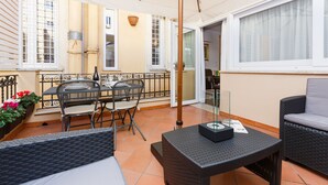 A sunlit patio with wicker furniture, a table, and a sofa. - Rome Boutique Apartments with terrace, whirlpool in room, central.   (6900335)