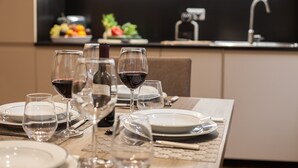 A dining table set with plates, glasses, and cutlery, with a kitchen area in the background. - Rome Boutique Apartments with terrace, whirlpool in room, central.   (6900335)