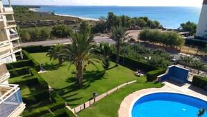 A residential area with a swimming pool, a well-maintained lawn, and a view of the sea.