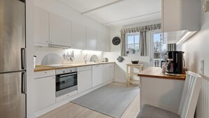 A modern kitchen with white cabinets, stainless steel appliances, and a wooden countertop.