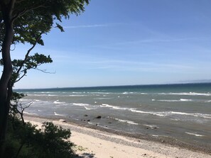 Ein Strand mit Wellen, einem klaren Himmel und weiter Küste.