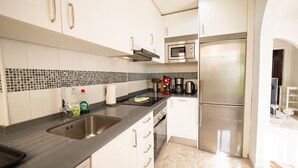 A modern kitchen with stainless steel appliances, white cabinets, and a black countertop. - Luxurious apartment with garden (Agaete)