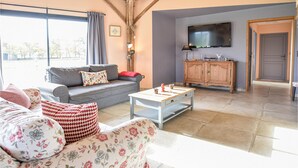 A living room with a grey sofa, floral-patterned couch, and a wooden cabinet. - 3 bedroom awesome home in Hattenville (Hattenville)