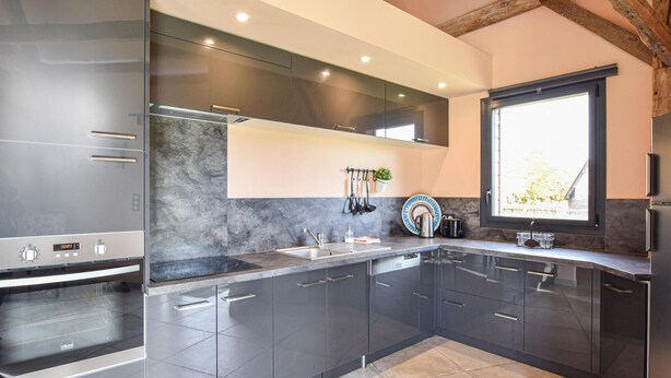 A modern kitchen with dark cabinetry, a built-in oven, and a window providing natural light. - 3 bedroom awesome home in Hattenville (Hattenville)