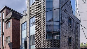 A modern building with a unique brick pattern facade, large windows, and a glass entrance. - The Phase Boutique Hotel (Seoul)