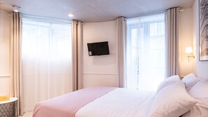A hotel room with a bed, a flat-screen TV mounted on the wall, a bedside table, and a lamp. - The Phase Boutique Hotel (Seoul)
