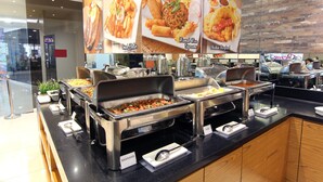 Area buffet con diverse postazioni cibo, tra cui una con salsicce.