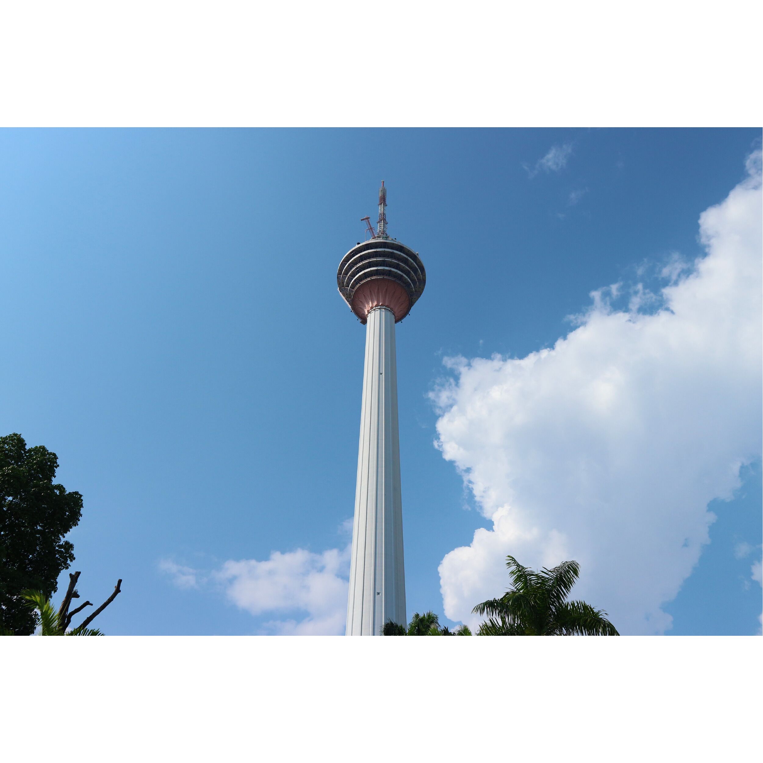 A tall tower with a spherical observation deck at the top, surrounded by clear blue sky and some clouds.