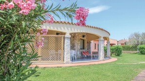 A covered outdoor seating area with a stone wall, a white chair, and a table. - Lovely home in Costa Rei -CA- (Costa Rei -CA-)