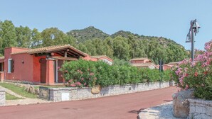 A red-roofed building with a stone wall and a paved road. - Lovely home in Costa Rei -CA- (Costa Rei -CA-)