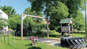 A playground with a swing set, tire swings, and a small wooden playhouse.