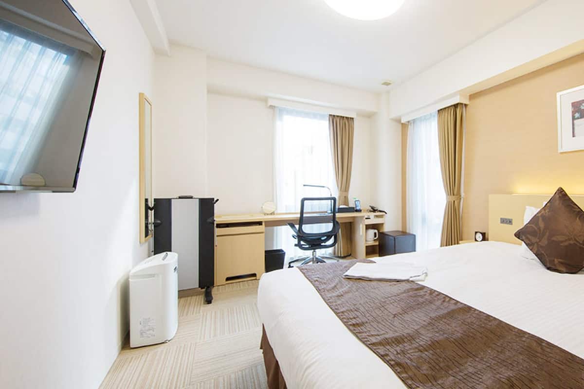 Une chambre d’hôtel avec un lit, un bureau, une chaise, une télévision et un tableau au mur.