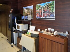 A hotel room with a minibar, a microwave, a refrigerator, and a coffee station.