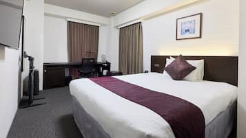 A hotel room with a large bed, a desk with a chair, a flat-screen TV, and a framed picture on the wall.