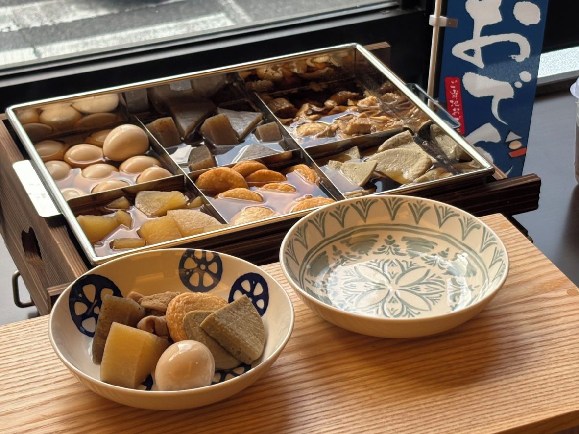 A tray of assorted food items and two bowls on a wooden table.