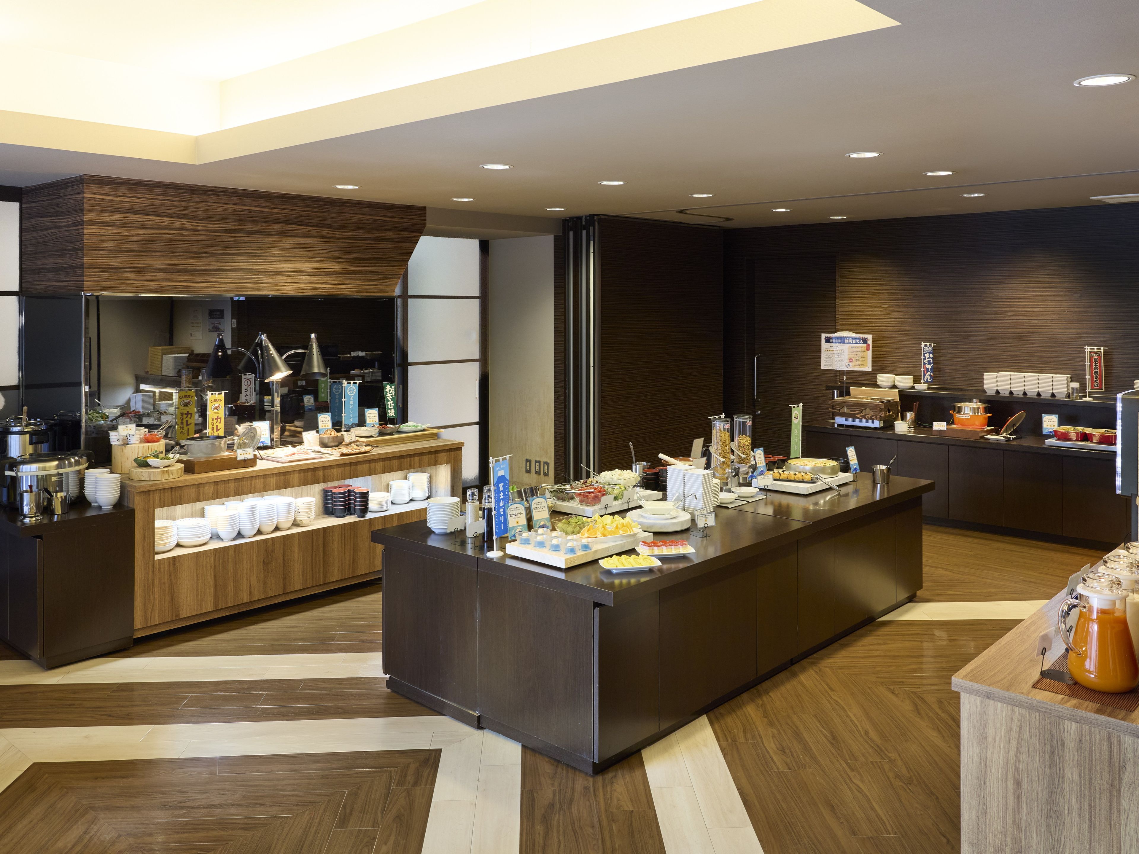 A modern hotel lobby with a reception desk, a buffet area, and a coffee station.