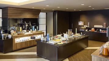 A modern hotel lobby with a reception desk, a buffet area, and a coffee station.