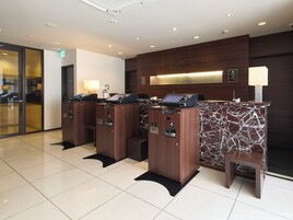 A reception area with a marble counter, a digital kiosk, and a seating area.